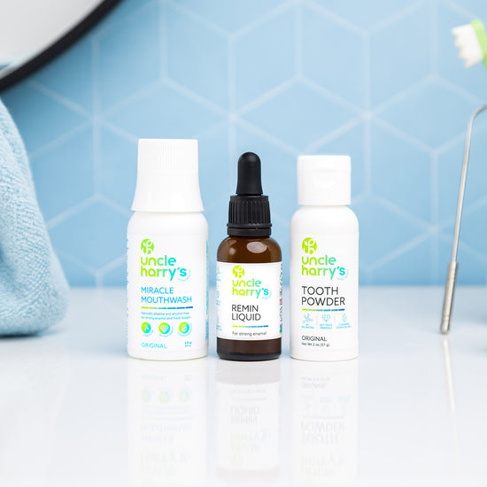 Uncle Harry's Mouthwash, Remin Liquid, Tooth Powder on a bathroom counter with a toothbrush and glass.