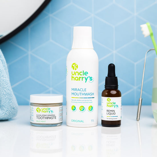 Collection of Uncle Harry's dental care products on a bathroom counter with a blue tiled wall background.