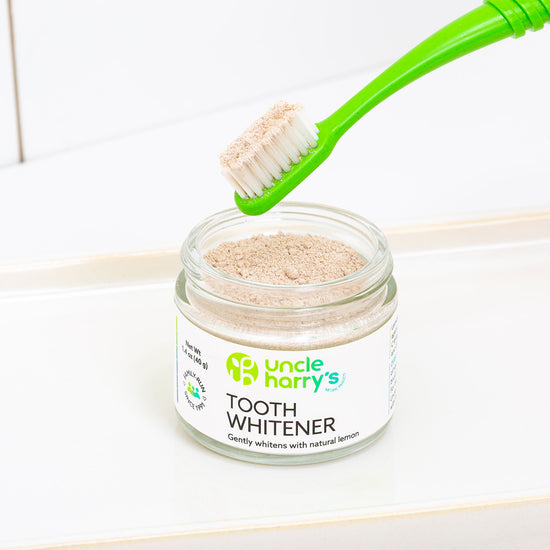 Jar of Uncle Harry's Tooth Whitener with a green toothbrush on a white background