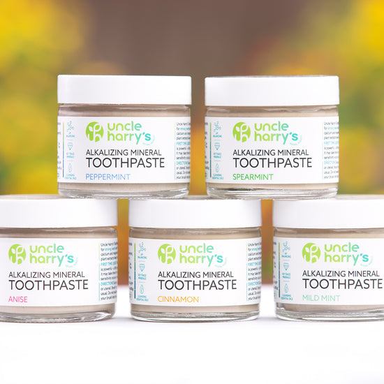 Five jars of Uncle Harry's Alkalizing Mineral Toothpaste on a white surface with a blurred natural background.