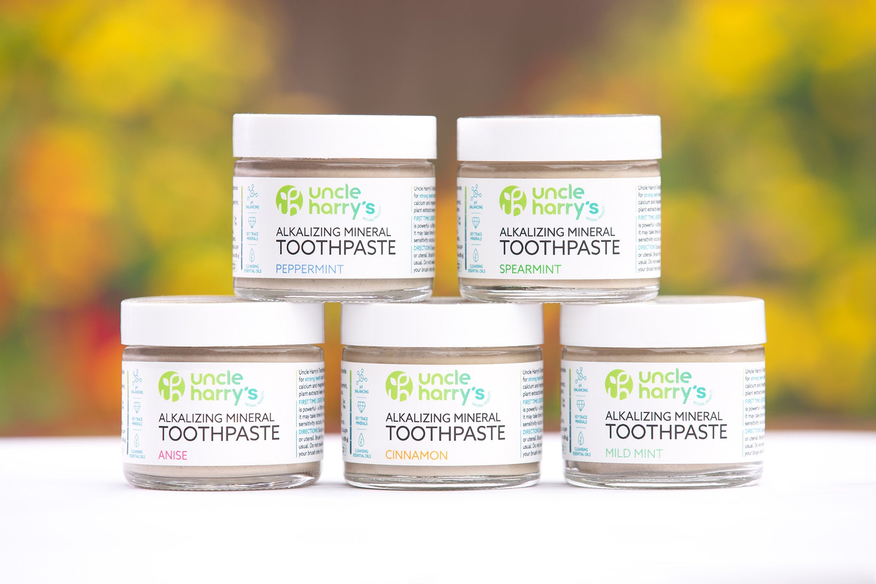 Five jars of Uncle Harry's Alkalizing Mineral Toothpaste on a white surface with a blurred natural background.