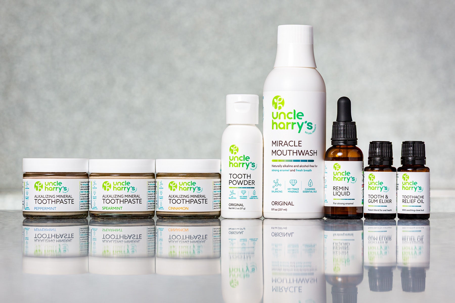 Collection of Uncle Harry's dental care products on a reflective surface with a gray background