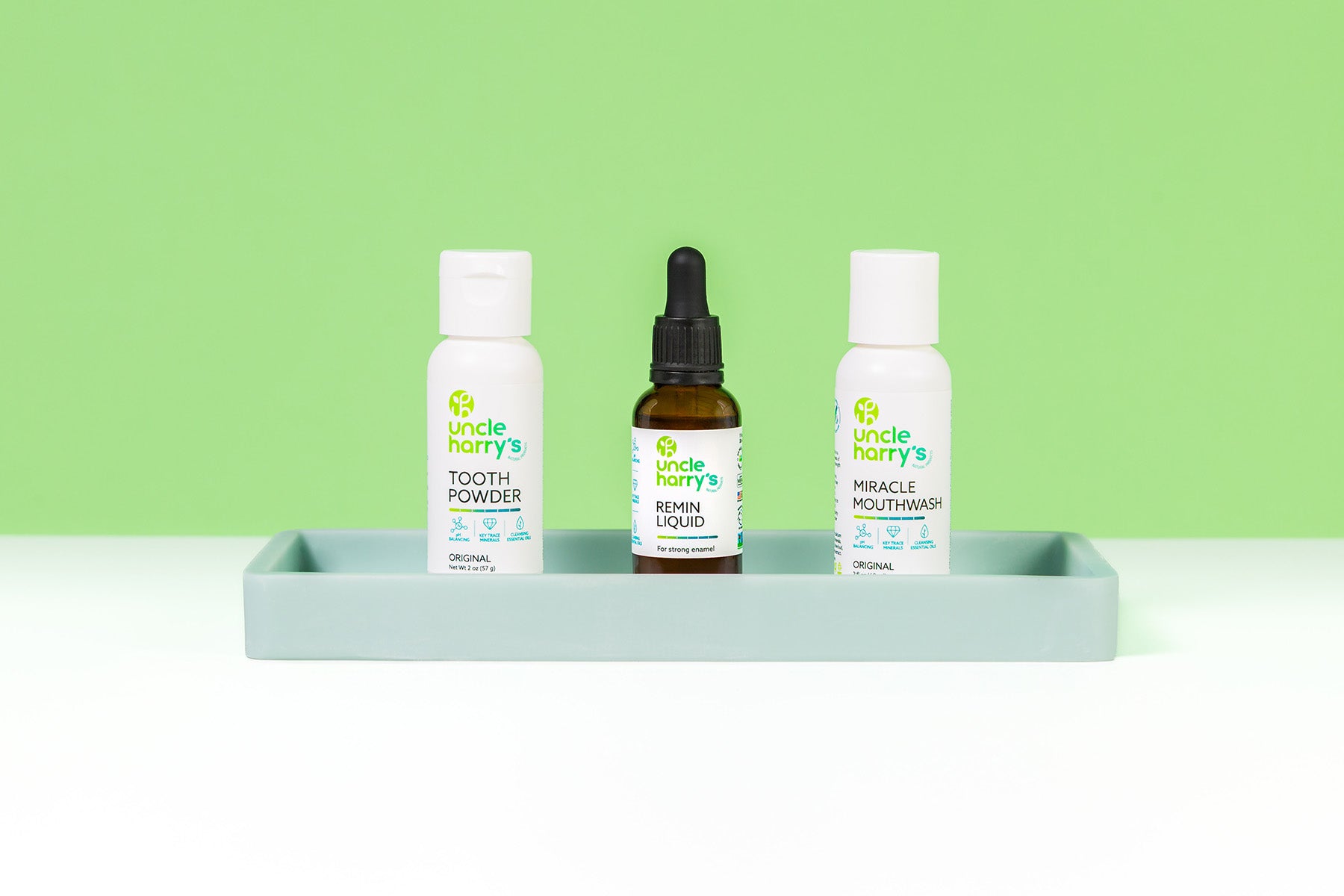 Uncle Harry's Tooth Powder, Remin Liquid, and Mouthwash on a gray tray with a green background