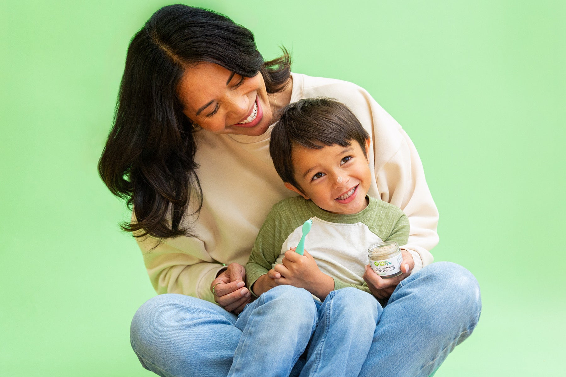 Woman and child sitting together on a green background