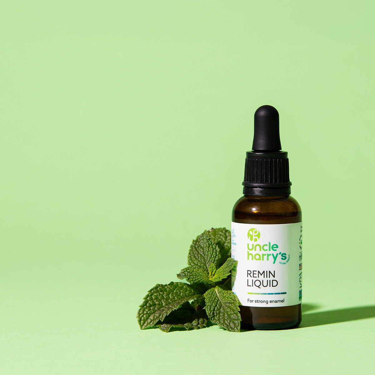 Bottle of Uncle Harry's Remin Liquid with mint leaves on a green background