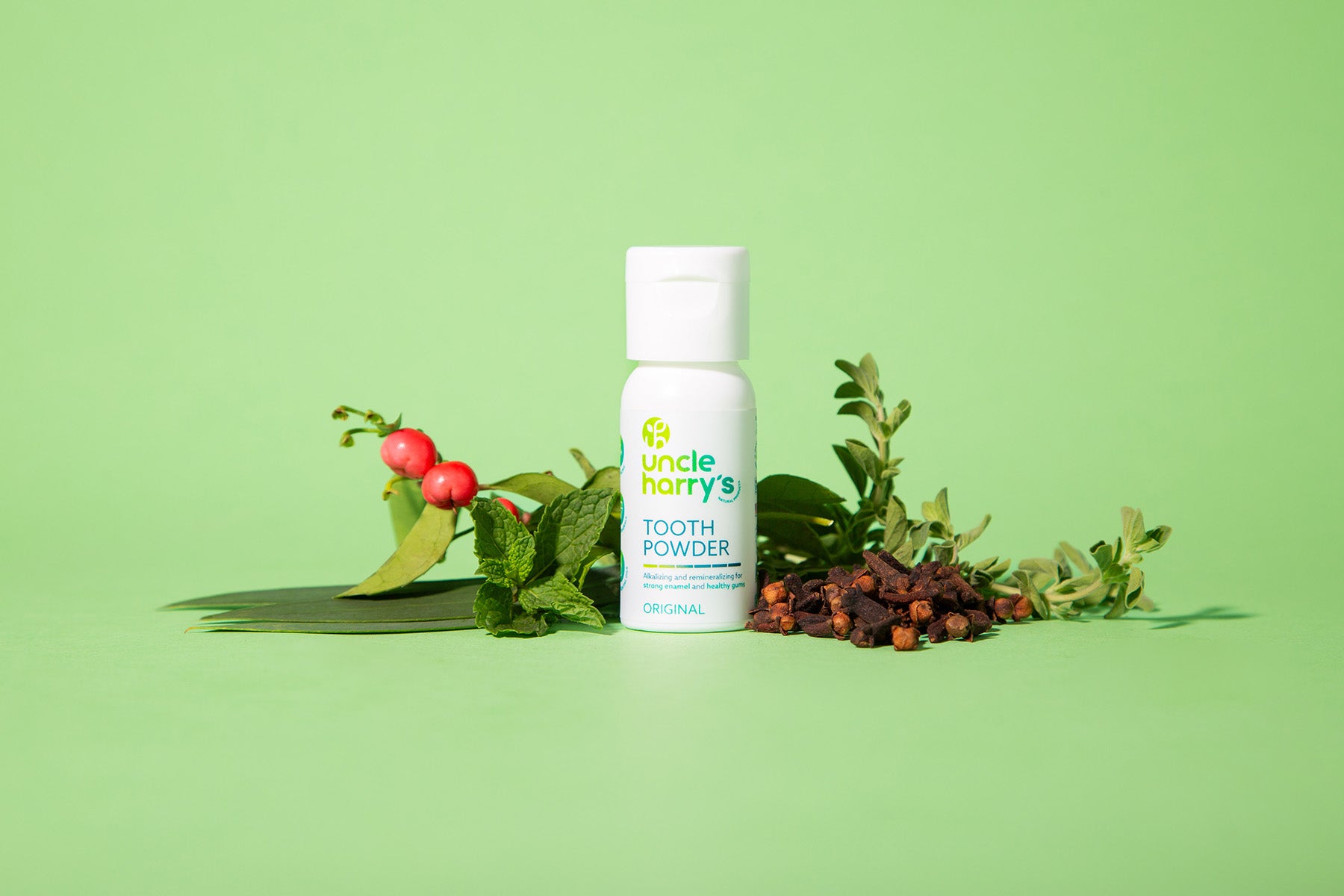 Uncle Harry's Tooth Powder bottle with natural ingredients on a green background
