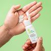 Hand holding a bottle of Uncle Harry's Tooth Powder with some powder on a green background
