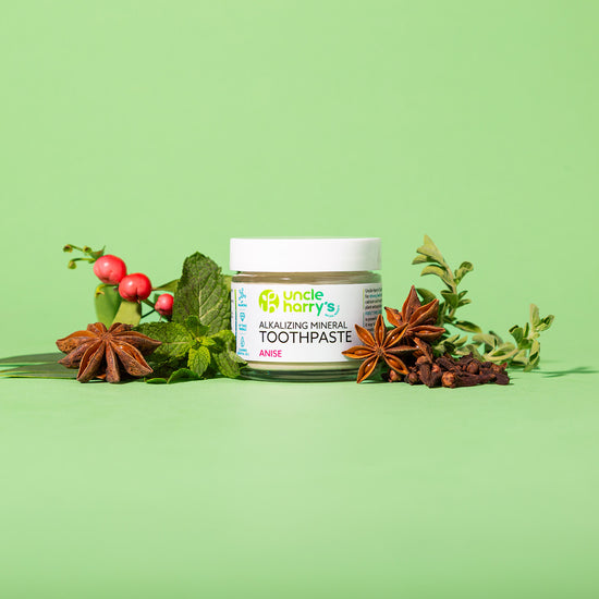 Jar of Uncle Harry's All-Natural Star Anise Toothpaste with herbs on a green background