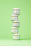 Five jars of Uncle Harry's Toothpaste stacked on a green background